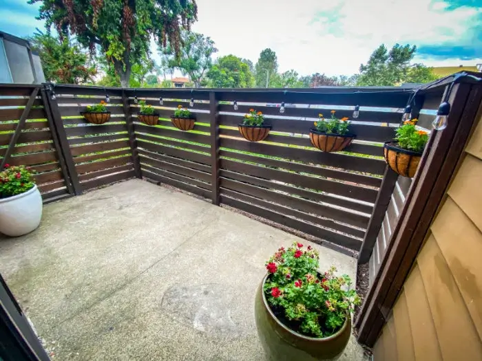 A patio with potted plants and a wooden slat fence.