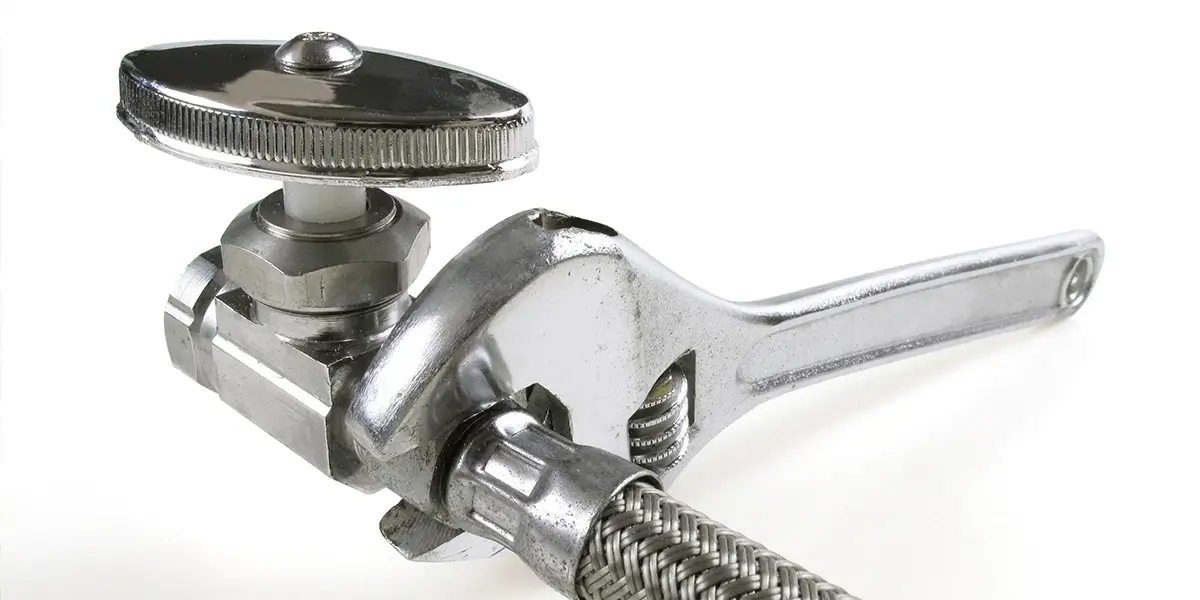 A Crescent wrench tightening stainless steel hose connection.