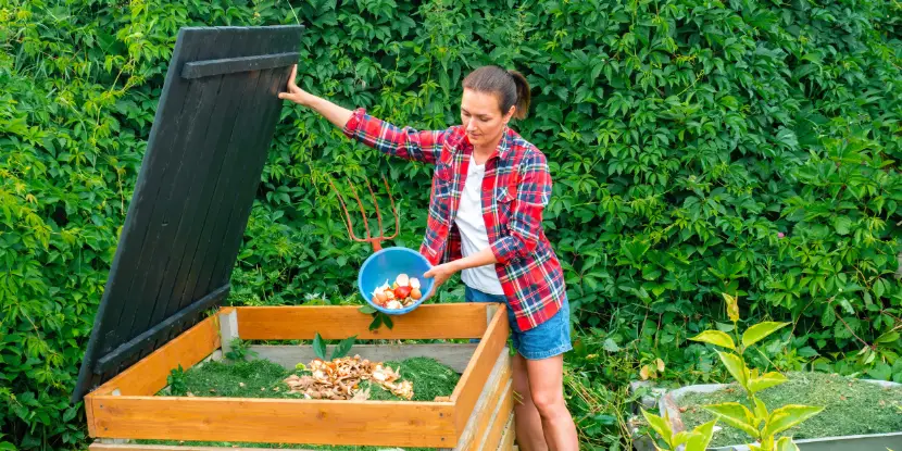 A woman emptying food scraps into a composting structure