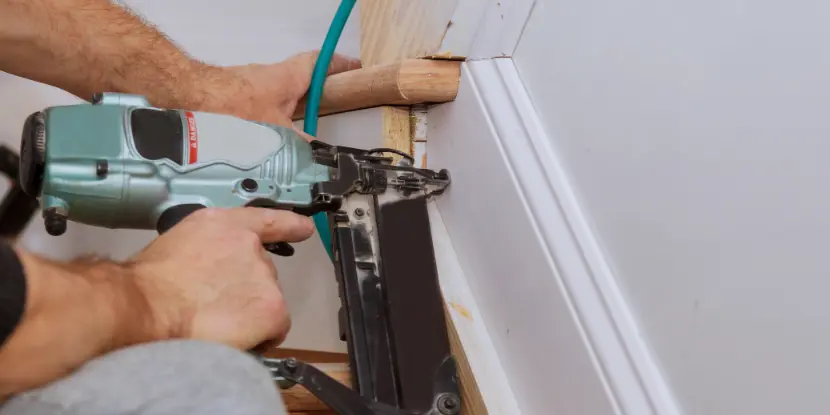 Attaching trim to a wall with a power nailer