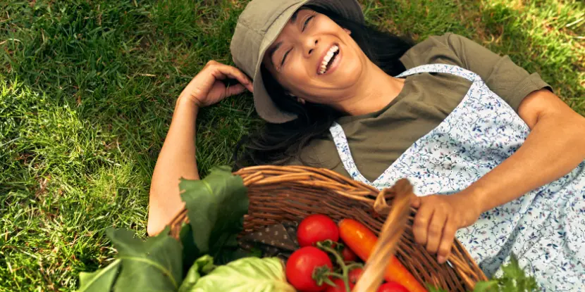 A woman lying in the grass next to her produce harvest