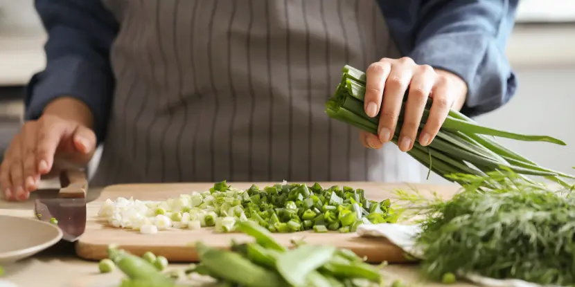 A cook chopping green onions