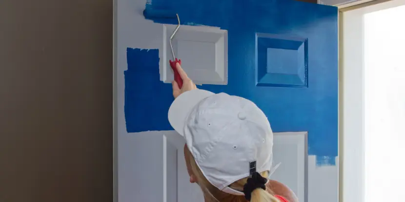 Woman painting a steel door blue