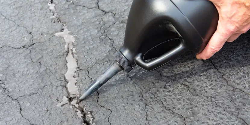 Man applying asphalt crack filler