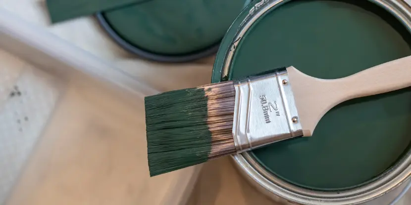 A paintbrush and hunter green paint