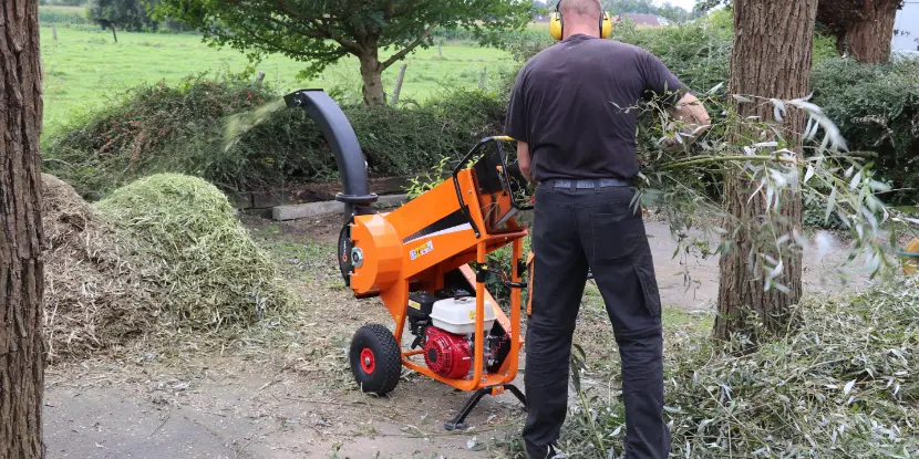 A man chipping branches into much