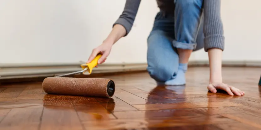 A woman applying stain with a roller