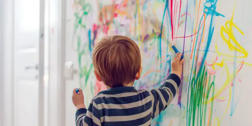 A child scribbles on a wall