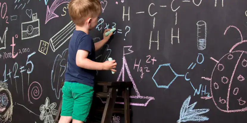 A boy does math on a chalkboard surface