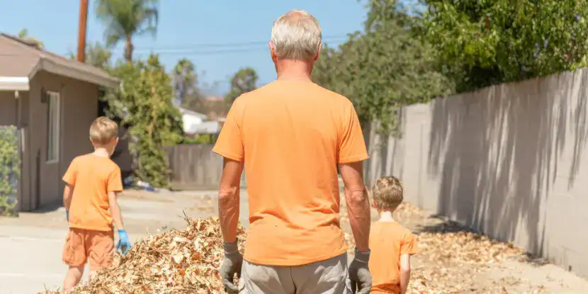 A grandfather and his grandsons clean the yard