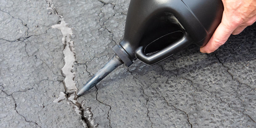A homeowner repairs driveway cracks