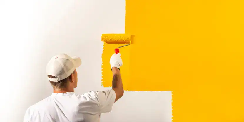 A man paints a wall yellow
