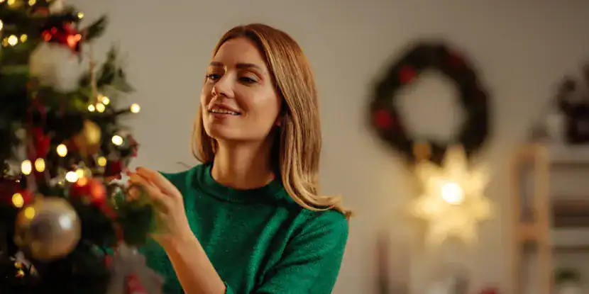 A woman trims a Christmas tree