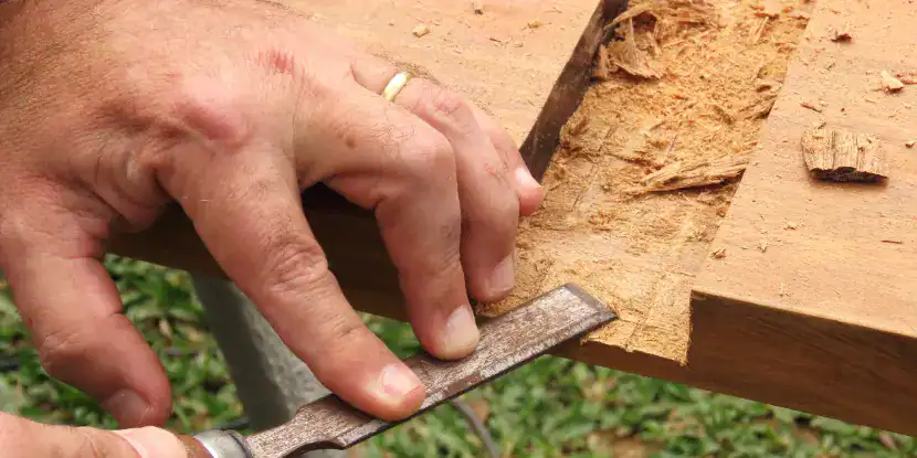 A worker uses a chisel to finish a joint.