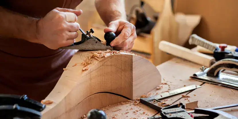 A woodworker shapes an irregular piece with a hand plane