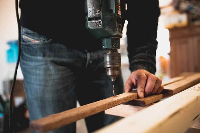 best-cordless-drill-buying-guide-1 Person using a cordless drill on a wood board, a common first test when choosing the best cordless drill