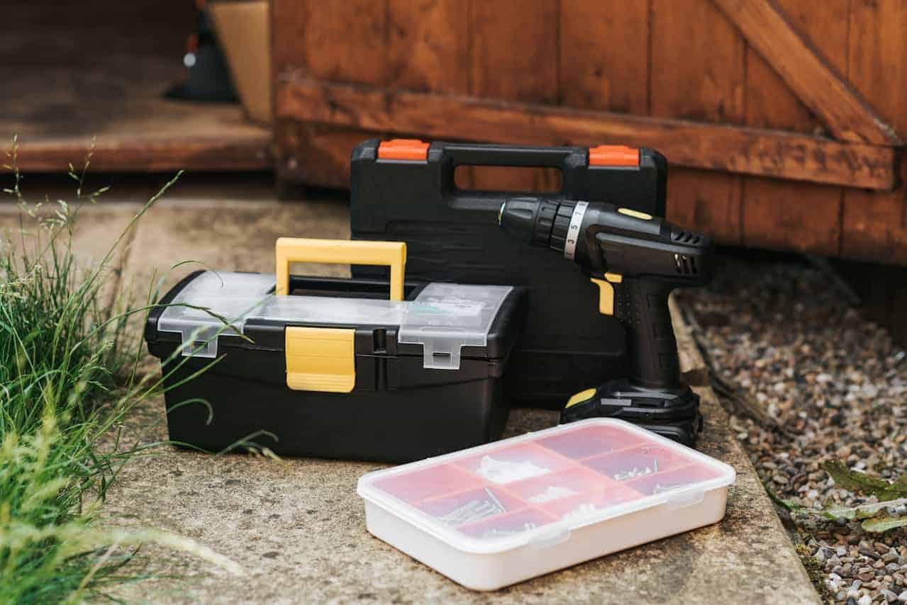 Cordless drill and toolbox with a parts organizer on the ground, ready for a home project